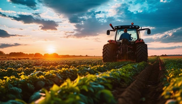 Farmer driving a tractor on a farm at sunset